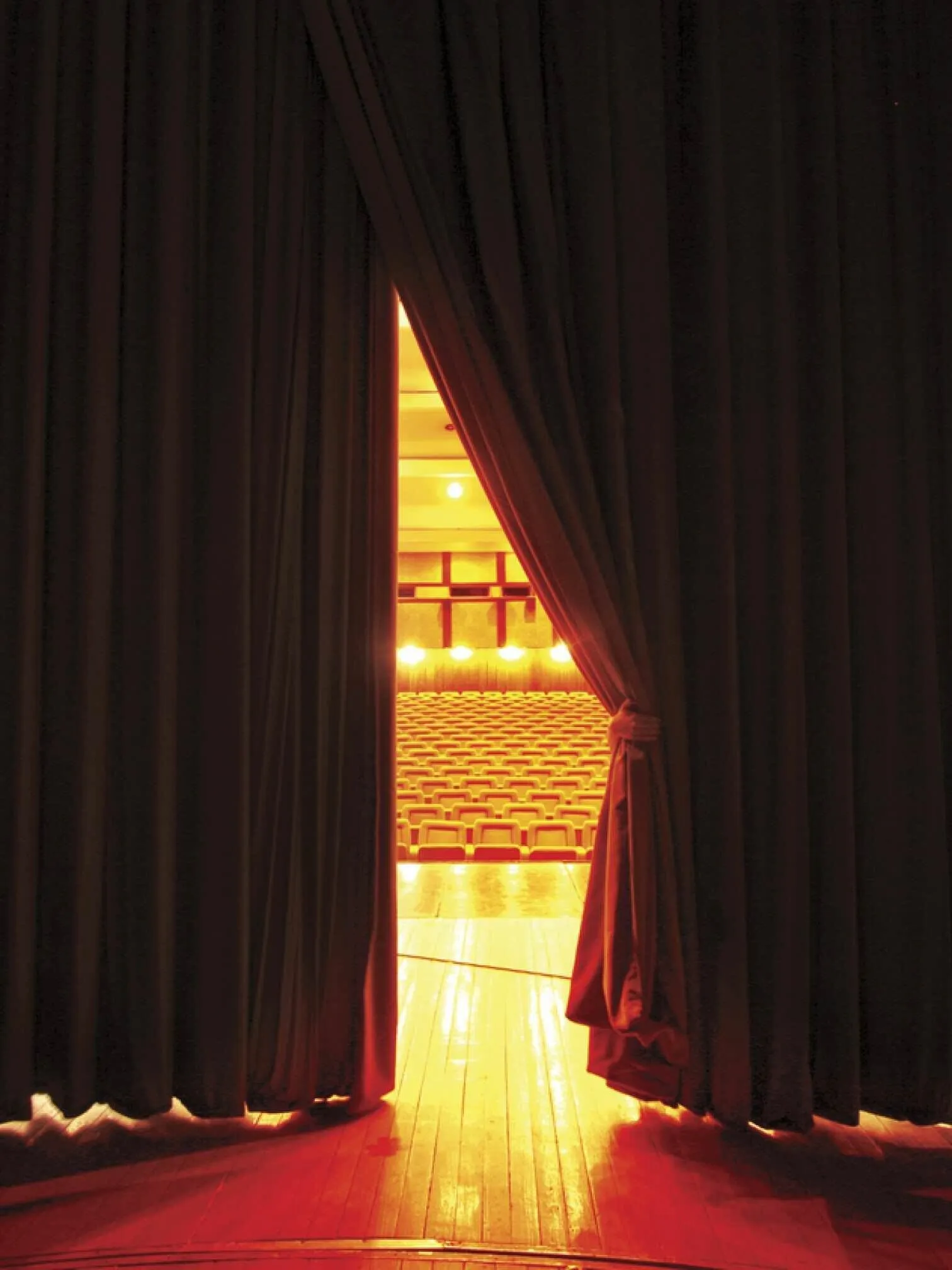 Closed theatre curtains with an opening revealing empty chairs